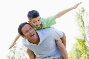 man with kid on his back smiling