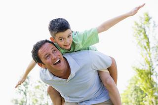 man with kid on his back smiling