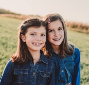 2 young girls smiling 1 with braces