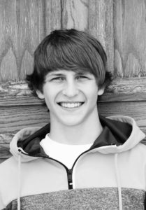 boy smiling against wooden background