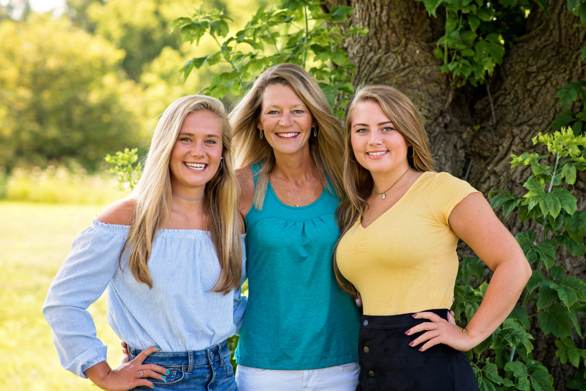 3 women smiling in front of a tree